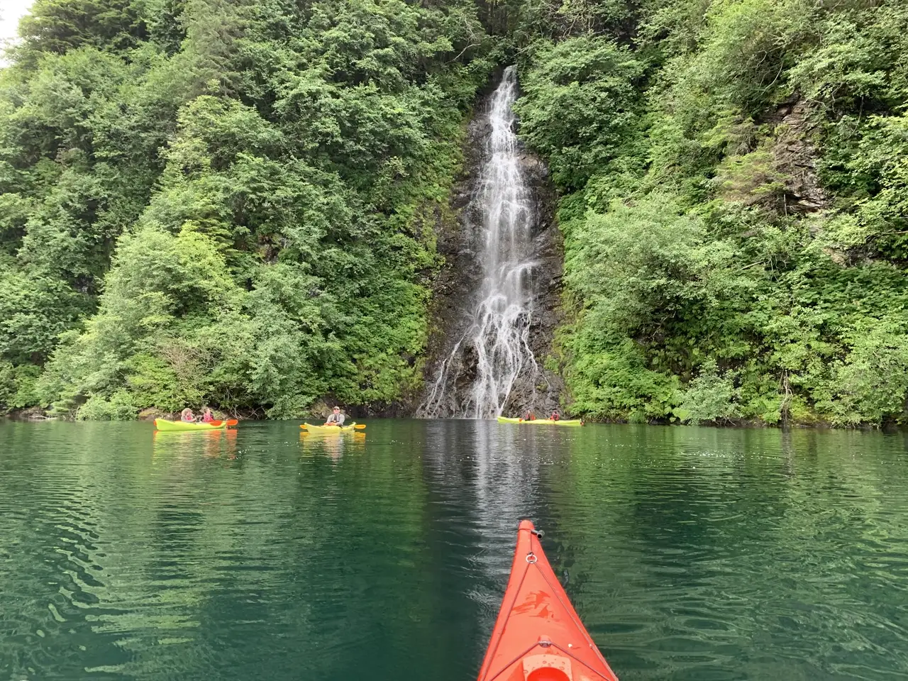 Kayakers approaching a waterfall in Sitka's rainforest